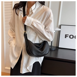 Détails du cuir grainé noir et des ferrures dorées sur le sac à bandoulière en demi-lune