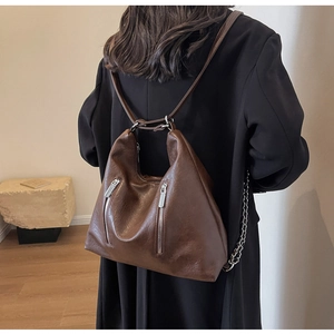 Detail of dark brown leather backpack with silver zippers and textured finish
