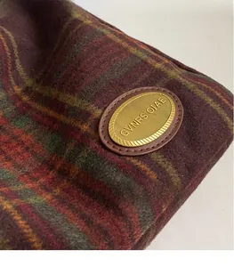 Detail of dark plaid tweed fabric texture and oval golden metal buckle on a shoulder bag