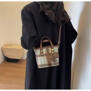 Mini sac seau en laine à carreaux avec poignées cuir et breloque chien sur modèle