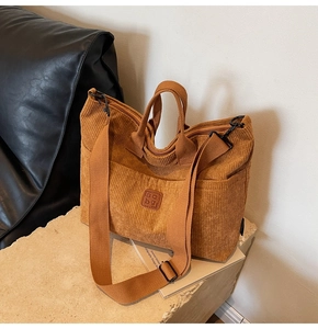 Detail view of the brown corduroy tote bag showing striped texture and leather logo patch
