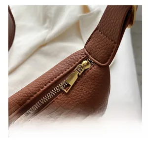 Detail of smooth golden metal zipper on premium brown lychee textured leather bag