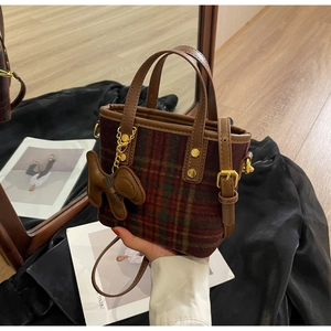 Détail du sac seau en laine à carreaux avec finitions en cuir et charme de chien