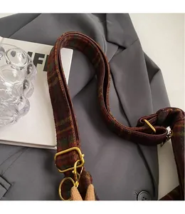 Detail of adjustable plaid wool shoulder strap with premium polished gold metal hardware