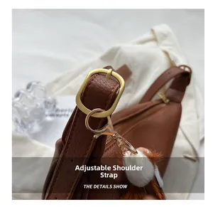 Detail of adjustable shoulder strap with gold buckle on brown lychee leather saddle bag