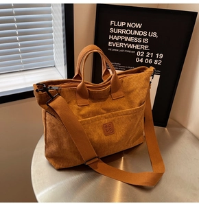 Detailed view of the corduroy tote bag showing metal table setting and side lighting