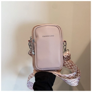 Détail de la pochette rose pâle texture litchi avec large bandoulière à motifs