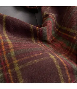 Macro texture of red plaid wool fabric showing yellow and green checkered weave detail