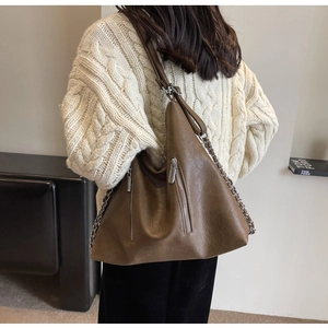 Detail of a brown PU leather hobo bag with silver chain straps and vertical zippers