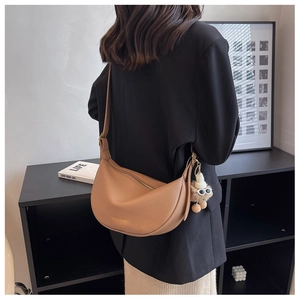 Detail of light brown lychee grain crescent bag with adjustable strap and plush pendant