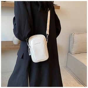 Gros plan d'un sac bandoulière beige avec texture litchi et bandoulière tissée