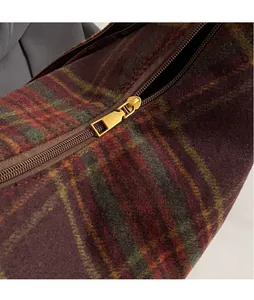 Detailed macro view of the gold-tone metal zipper and textured plaid wool fabric