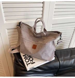 Detail of light grey corduroy tote bag showing scbg leather logo and front pocket