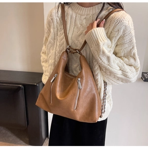 Detail of caramel hobo bag featuring litchi grain texture and silver zipper accents