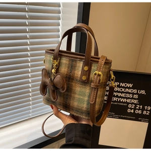Détail du sac seau à carreaux en laine avec anse en cuir marron et breloque chiot