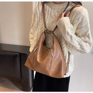 Brown leather convertible chain backpack on model with textured cream sweater