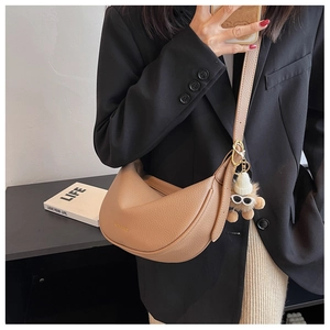 Detail of khaki pebbled leather crescent bag with gold text and plush bear charm