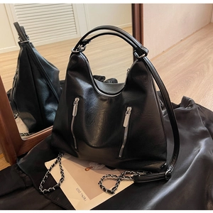 Detail of black large-capacity leather backpack with silver zippers and chain strap
