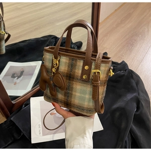 Détail du sac seau en laine avec pendentif ours marron et finitions dorées