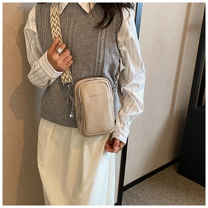 Détail du sac bandoulière en cuir beige avec sangle large géométrique et zip argenté