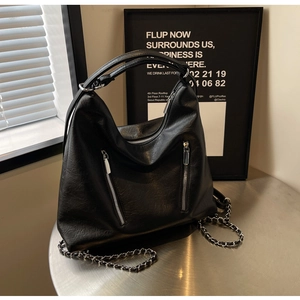 Detail of premium lychee texture leather and silver zipper pockets on a black tote bag
