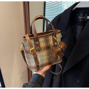 Détail macro du mini sac cabas en laine à carreaux avec finitions en cuir marron