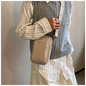 Détail du sac à bandoulière crème avec texture grainée et sangle jacquard élégante