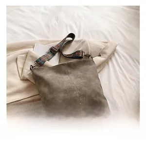 Detail of vintage bucket bag featuring textured faux suede and patterned wide strap