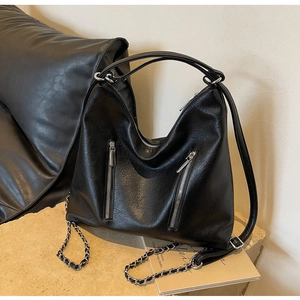 Detail of black leather hobo bag with silver chain straps and functional zippers