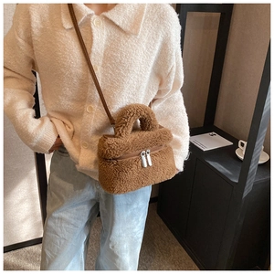 Detail der braunen Plüschtasche aus Lammfellimitat mit silbernen Reißverschlüssen und Griff