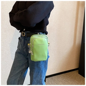 Détail du sac bandoulière en cuir vert vif avec double fermeture et breloque en métal