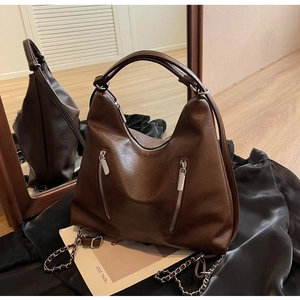 Detail of dark brown leather hobo bag with silver zippers and metal chain strap