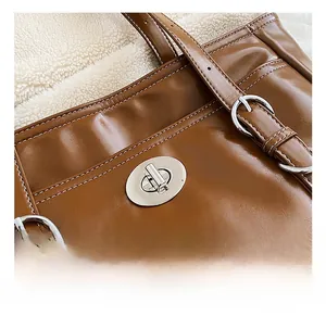 Detail of brown leather tote featuring silver twist lock and white contrast stitching