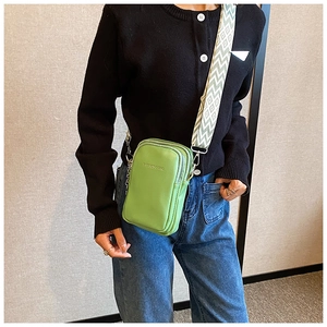 Détail du mini sac bandoulière vert avec sangle large à motifs et doubles zips