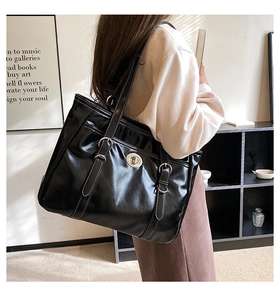 Detail of a large black leather tote bag with silver hardware on a shoulder strap model