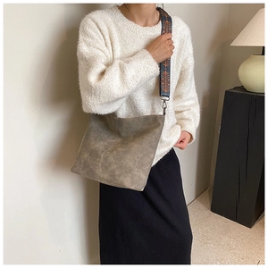 Close-up of vintage textured leather bucket bag with bohemian woven wide shoulder strap