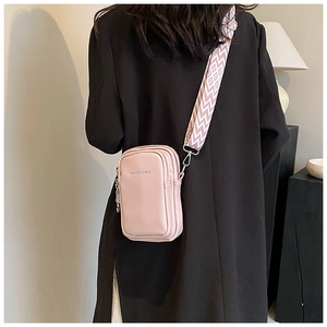 Détail d'un sac à bandoulière rose avec une large sangle tissée de style ethnique