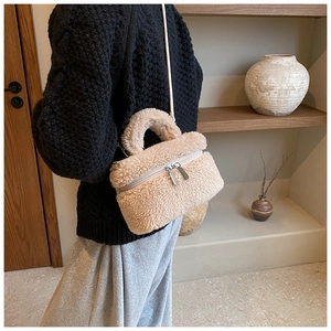 Detail van beige pluizige emmertas met zilveren dubbele rits en pluche textuur op model