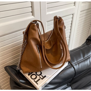 Detail of a large brown faux leather tote with vintage texture and silver chains