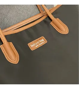 Detail of nylon fabric texture and leather logo patch on a large contrast tote bag