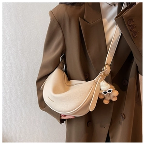 Close-up of beige lychee texture leather hobo bag with a cute bear plush charm