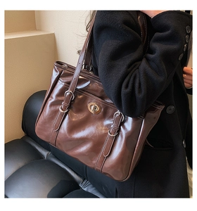 Detail view of large brown tote bag featuring glossy leather finish and retro metal lock