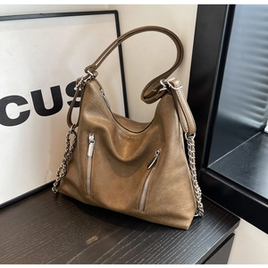 Detail of hobo bag featuring dual vertical zippers and silver chain on textured PU leather