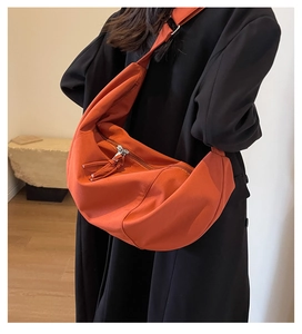 Détail du sac à bandoulière orange en toile en forme de lune avec gland de fermeture