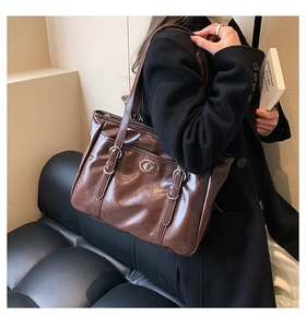 Detail of dark brown tote bag featuring vintage metal twist lock and adjustable straps