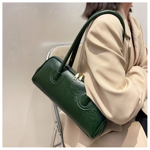 Detail of dark green leather shoulder bag with gold dual-zipper and reinforced stitching