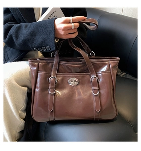 Close-up of brown patent leather tote bag with silver twist lock and buckle details