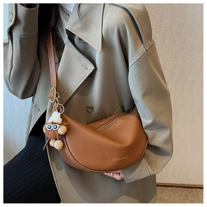 Detail of brown litchi pattern saddle bag with gold lettering and cute plush pendant