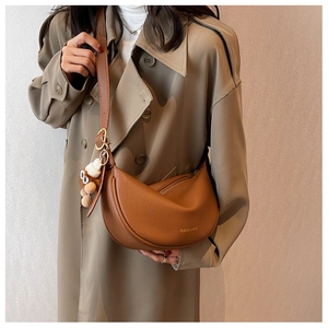 Close-up of brown lychee leather saddle bag with gold zipper and fashion text