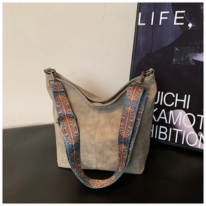 Detail of grey vintage bucket bag featuring a colorful geometric woven wide shoulder strap